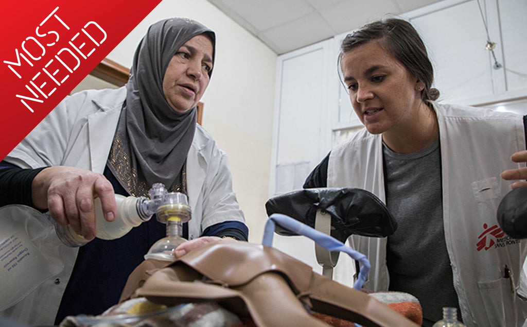 Two MSF staff, one holds a manual resuscitator over a medical dummy.