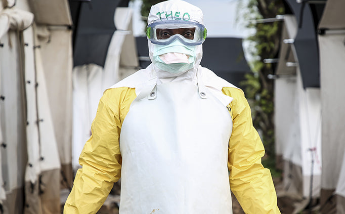 A person wearing head to toe, white and yellow personal protective equipment.