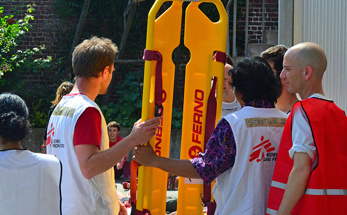 A group of MSF staff stand with a yellow stretcher.