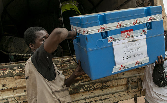 Two MSF staff carry a blue cooler.