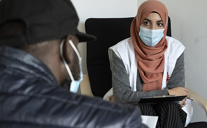 An MSF staff sits in consultation and conversation with a patient.