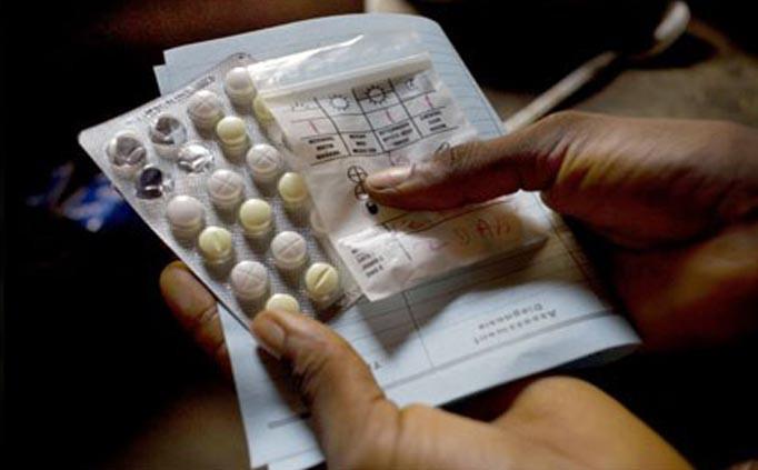 Hands holding a blister pack of white and yellow pills.